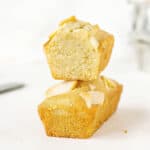 White background with stack of whole and halved small almond rectangular cakes.