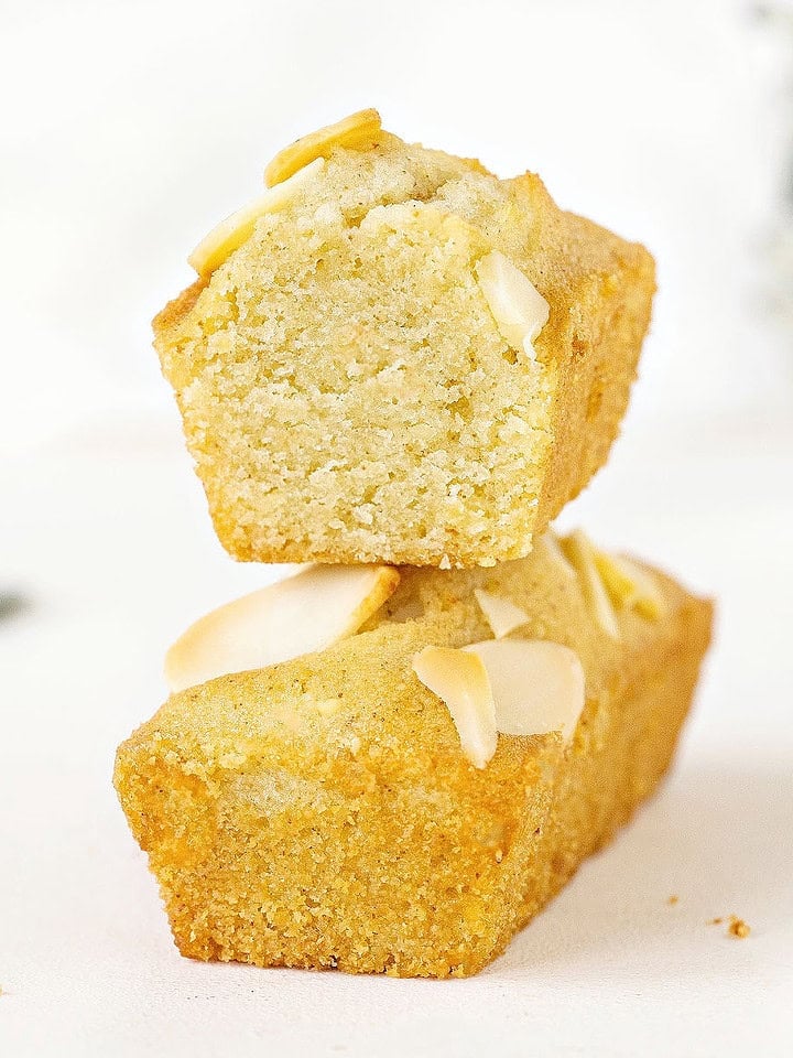 White background with stack of whole and halved small almond rectangular cakes.