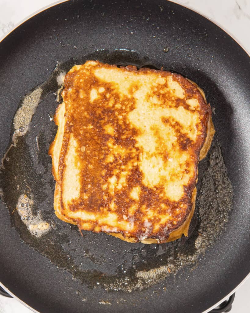 French toast cooking on a dark skillet. Top view, close up.