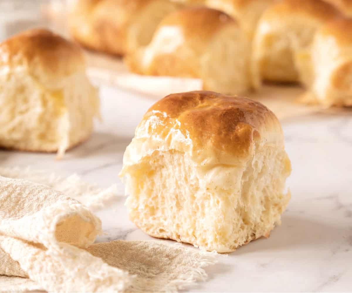 Soft dinner roll on a white marbled surface. More rolls in the background.