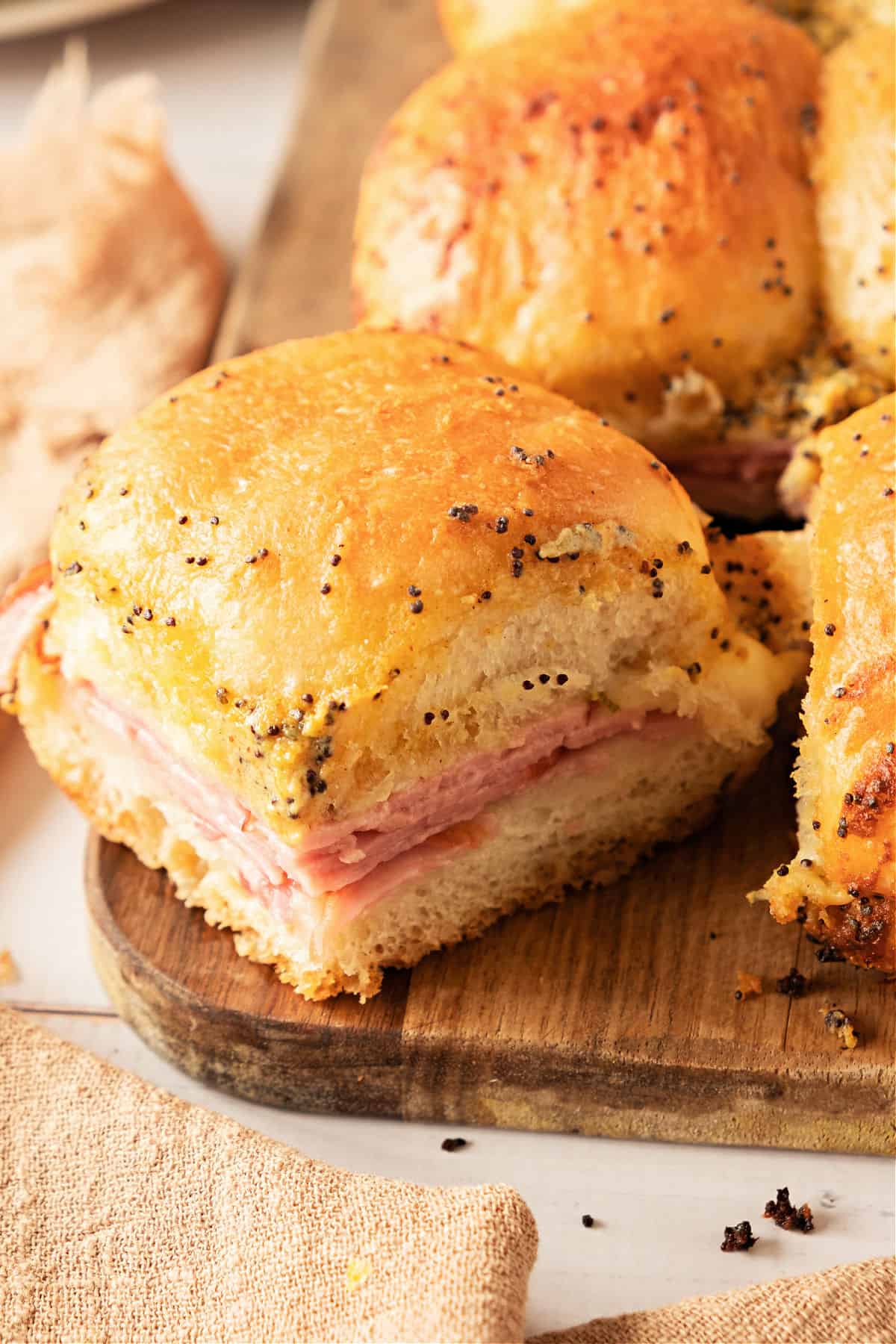 Wooden board with ham and cheese sandwiches with poppy seeds. 