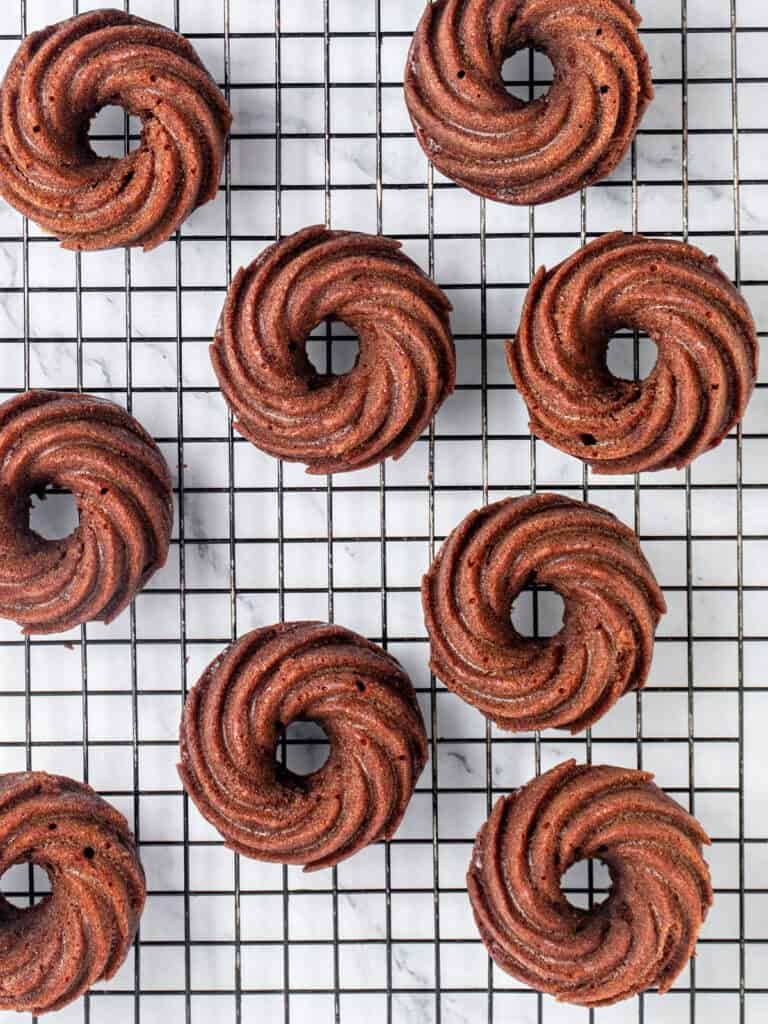 Black wire rack with mini chocolate bundt cakes. Top view. White background.