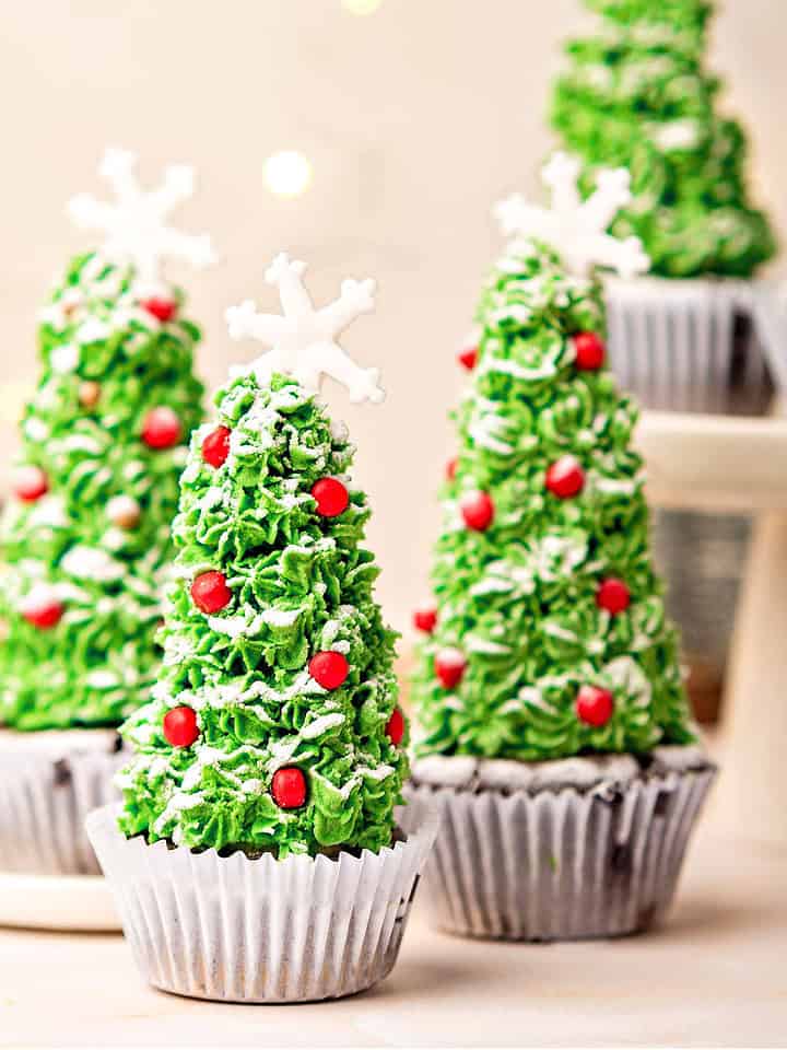 Christmas tree cupcakes in white paper liners. Beige background. Festive decorations.