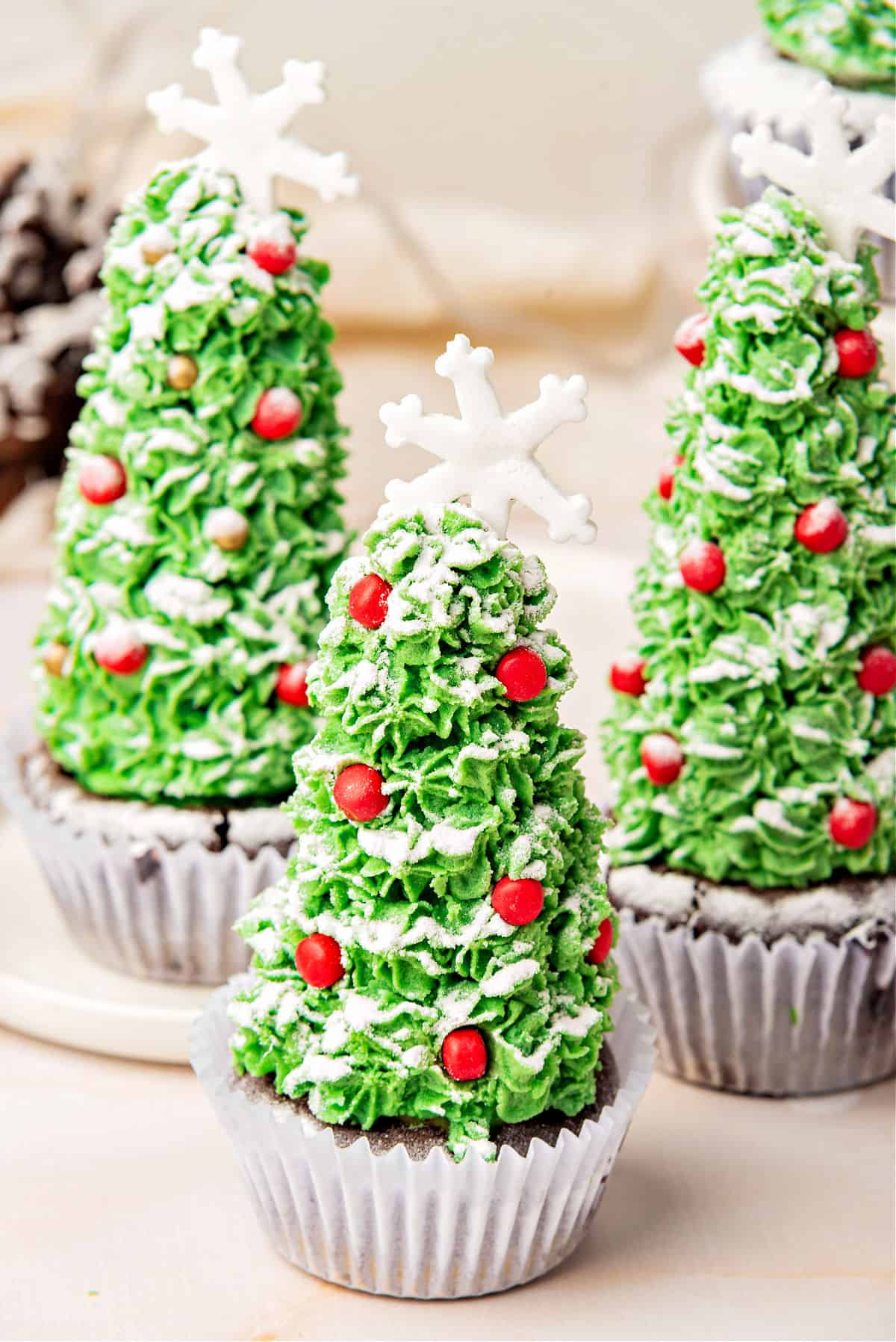 Decorated Christmas tree cupcakes in paper liners. Whitish surface and background.