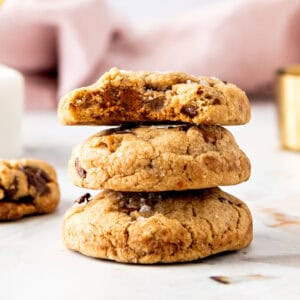 Stack of biscoff chocolate chip cookies. White surface, pink background.