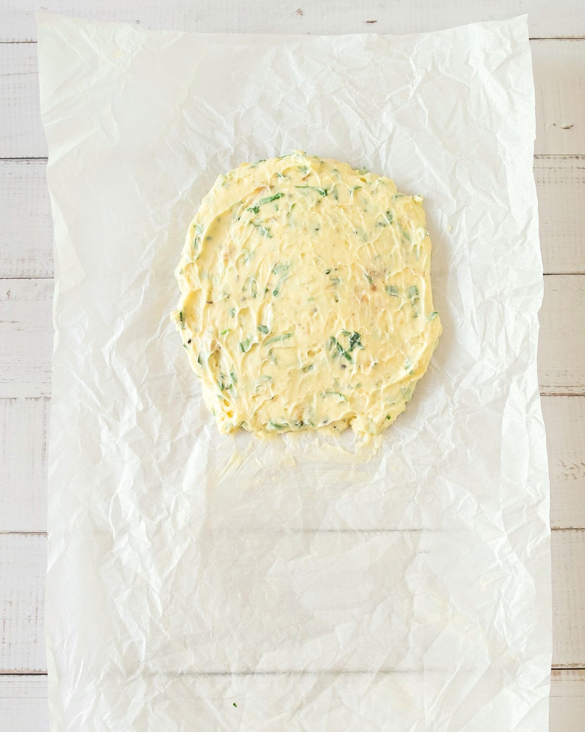 Parchment paper with disc of garlic butter mixture. Top view.