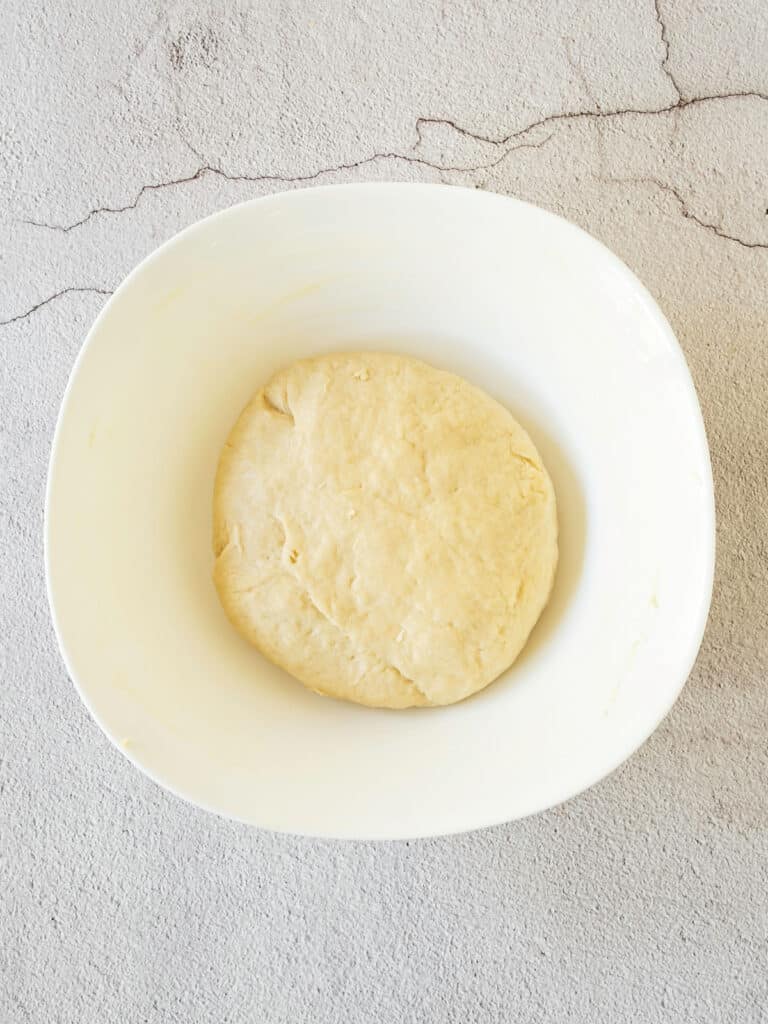 Yeasted dough for donuts in a white bowl. Cement background, top view.