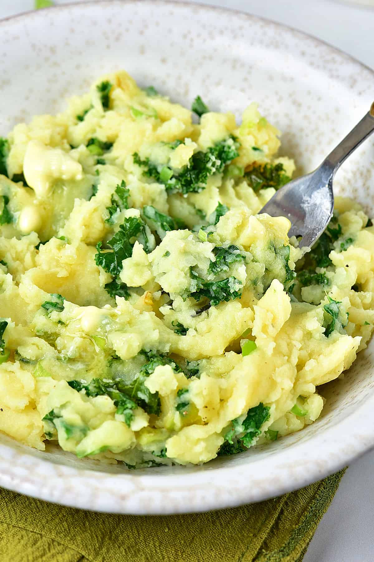 Close up gray plate with mashed potatoes with kale. A silver fork.