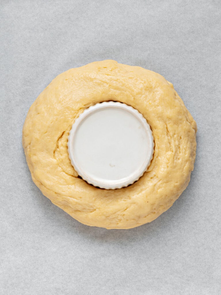 White rameking in the center of a dough ring before rising. Light gray background.