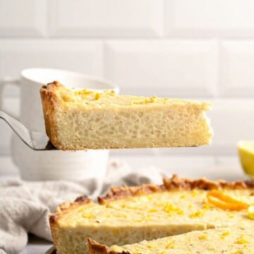White tile background with rice ricotta tart slice on a cake server. Whole tart below.
