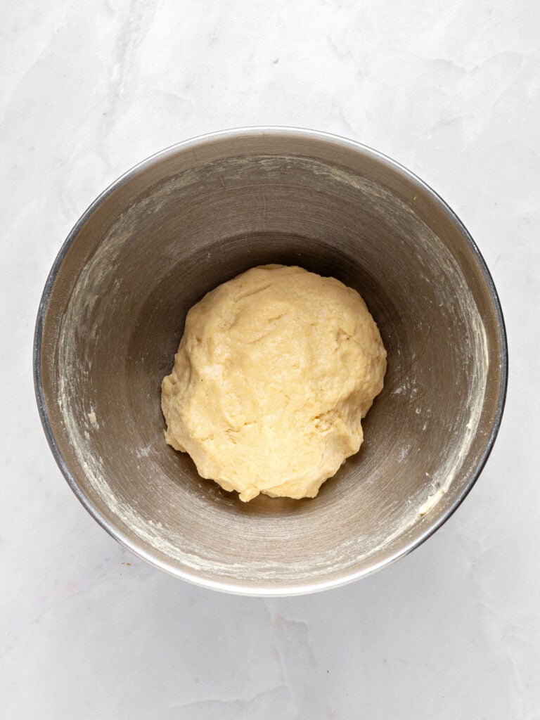 Metal bowl with sweet dough. Top view. Light gray background.