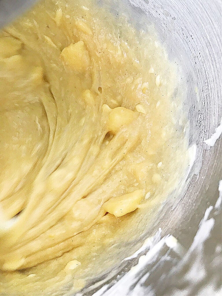 Butter added to dough in a metal bowl. Close up.