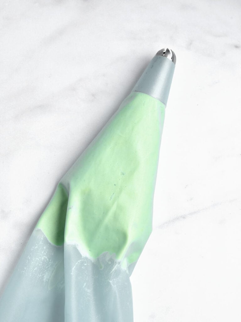 Piping bag with avocado filling on a white marbled surface.