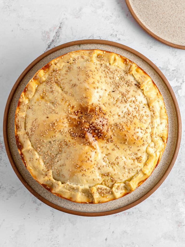 Top view of double-crusted pie on a beige plate. Light gray background.