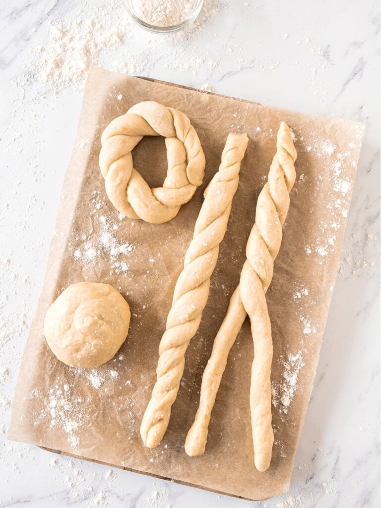 Ropes, ball and braid made with dough on beige parchment paper.