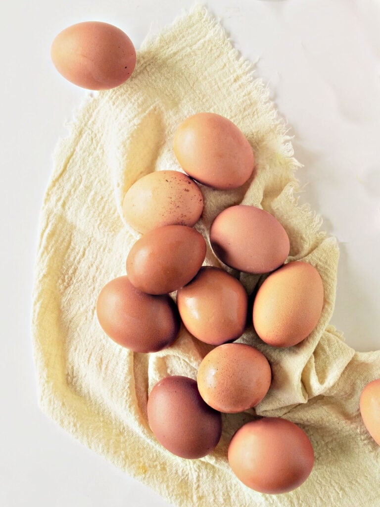 Several brown eggs on a beige cloth and white surface. Top view.