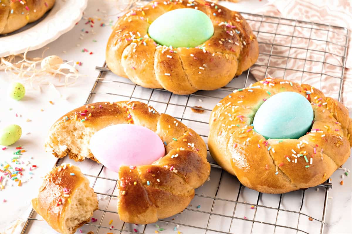 Wire rack with torn and whole Easter braids with dyed eggs and sprinkles.