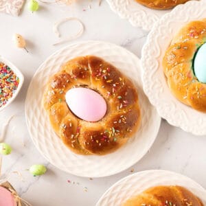 Individual braids with colored eggs and sprinkles on white plates. White background.