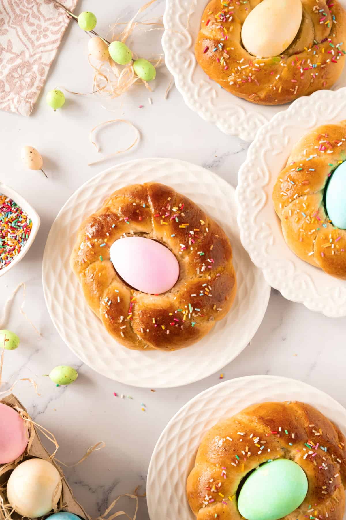 Top view of white plates with individual braids with colored eggs. White background.