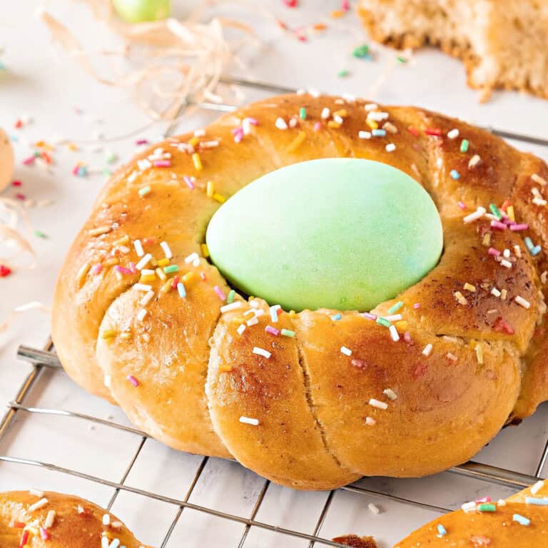 Close up Easter braid with green egg and sprinkles on a wire rack. White background.