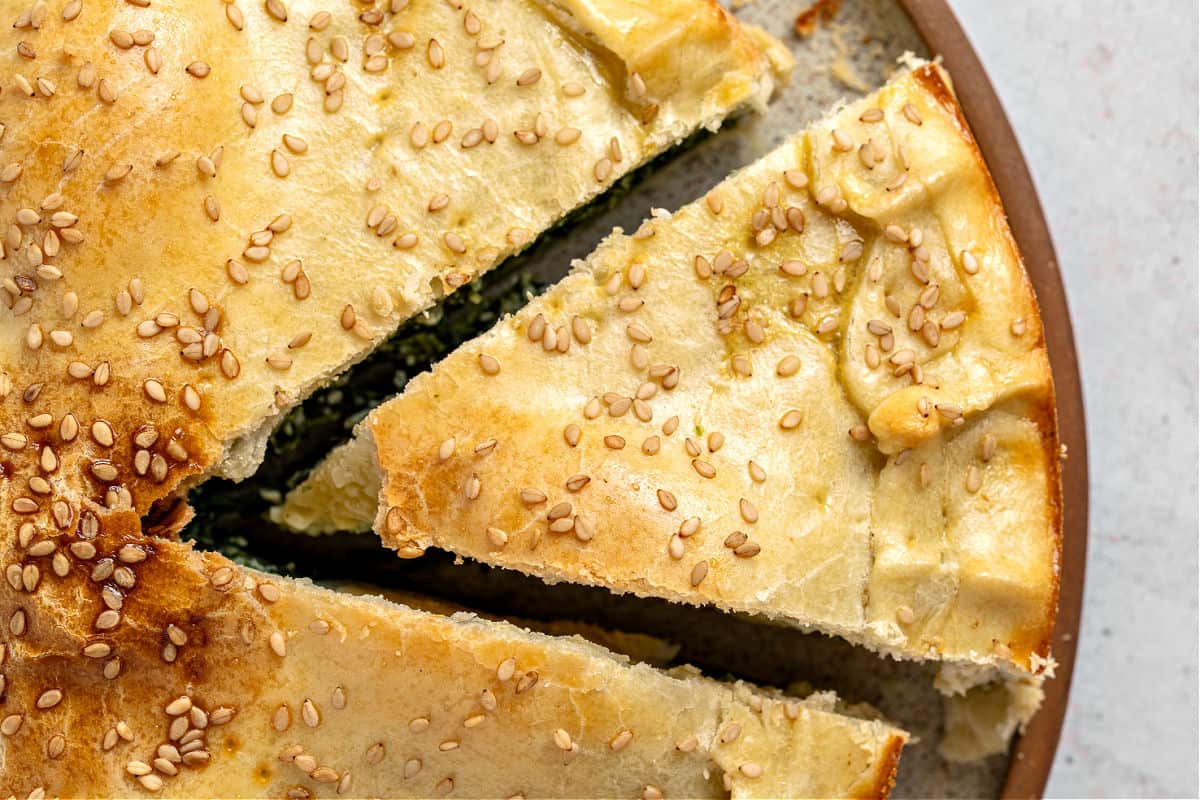 Golden top crust of Easter pie with sesame seed and cut slice.