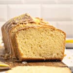 Stacked slices of glazed lemon pound cake. White tile background.