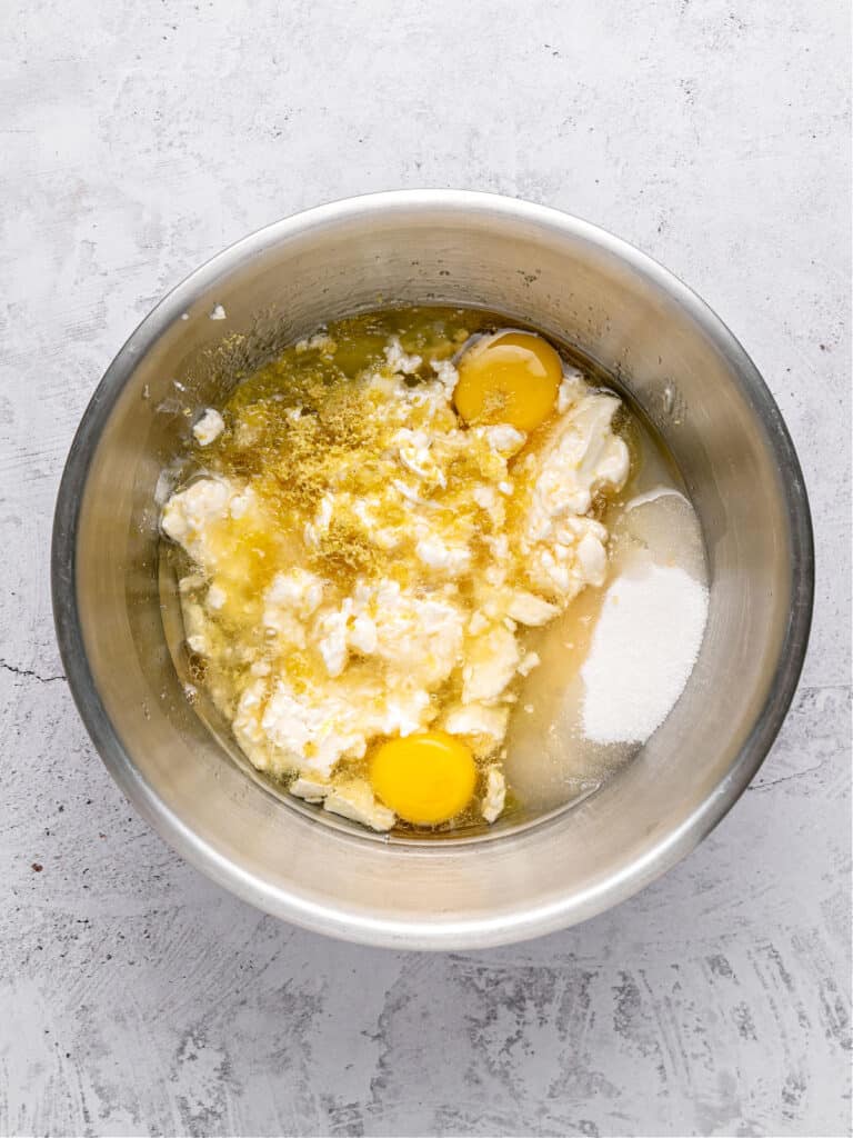 Metal bowl with wet ingredients for lemon cake. Light gray background.
