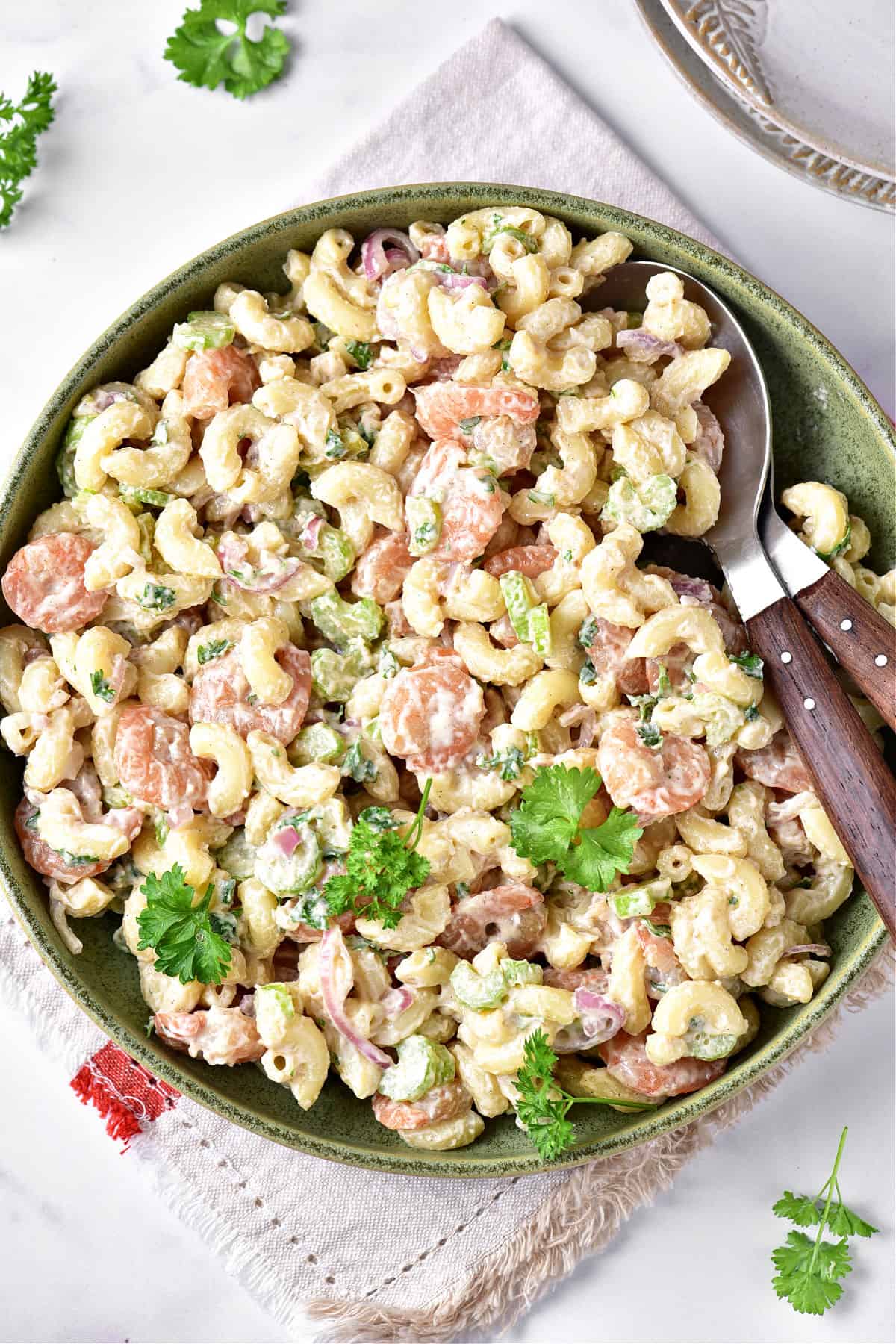 Green plate with shrimp pasta salad. White background and cloth. Parsley leaves.