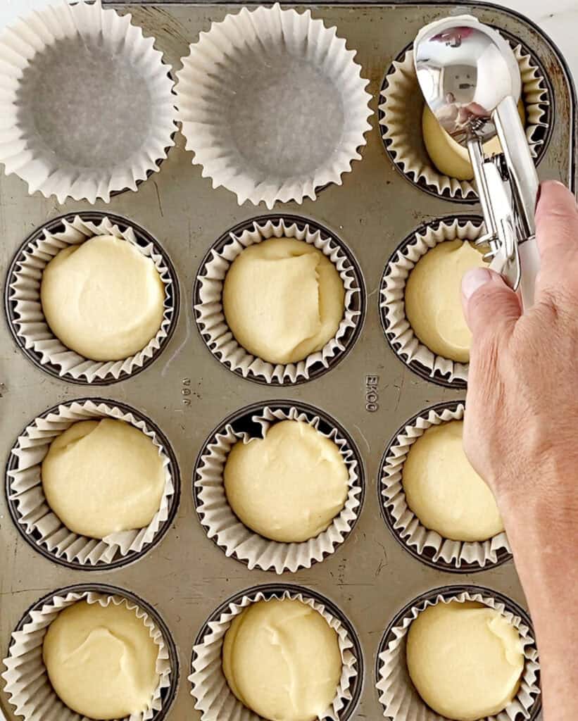 Scooping cake batter into paper liners. Metal pan.