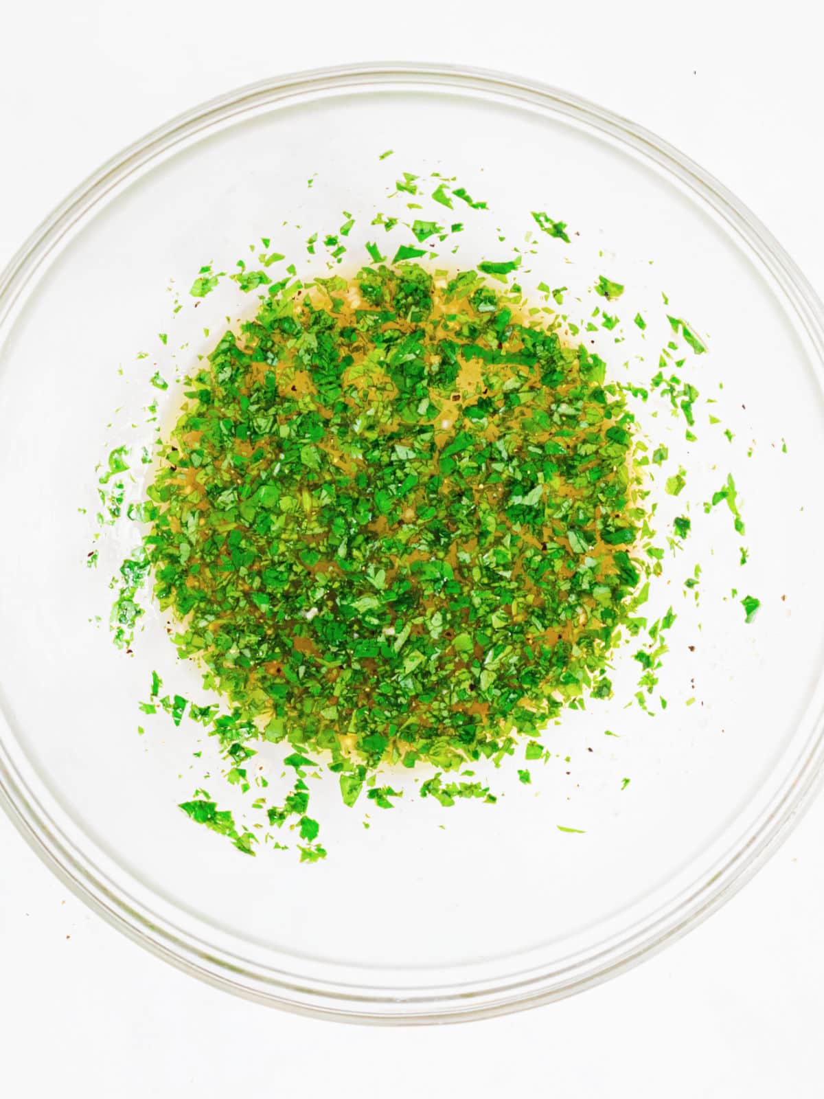 Glass bowl with cilantro lime dressing. White background, top view.