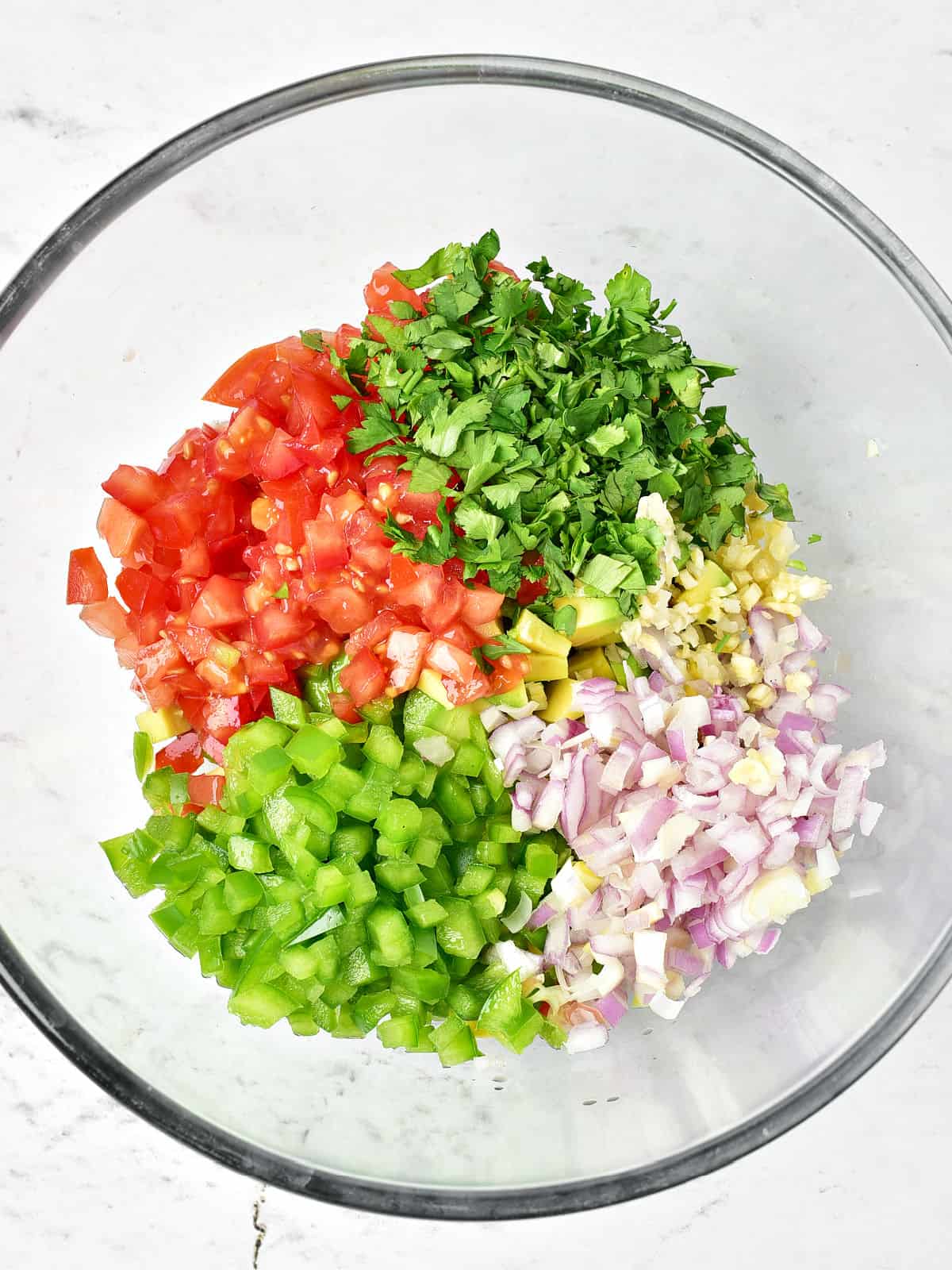 Glass bowl with chopped peppers, cilantro, red onion and tomatoes.