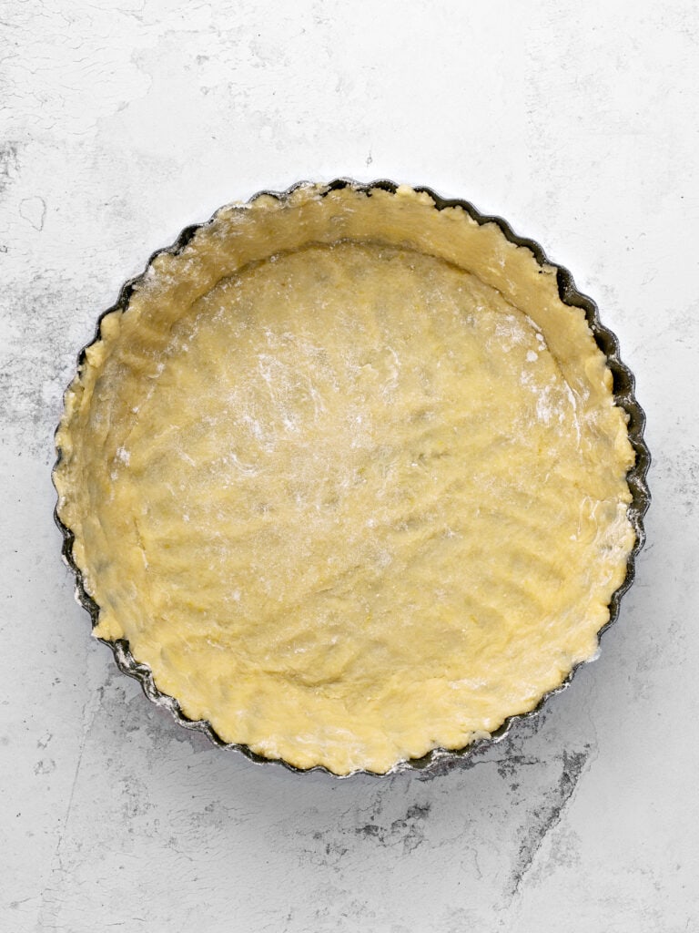 Lined dark metal pie pan with crust. Light gray background, top view.
