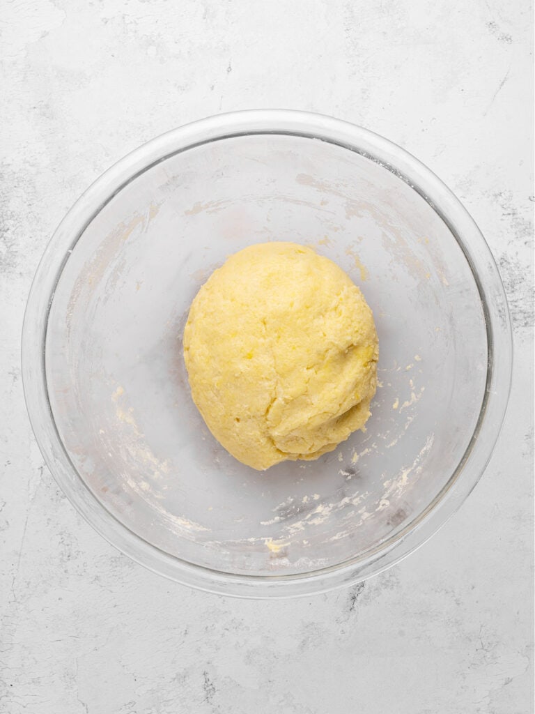 Ball of pie dough in a glass bowl. Light gray background, top view.