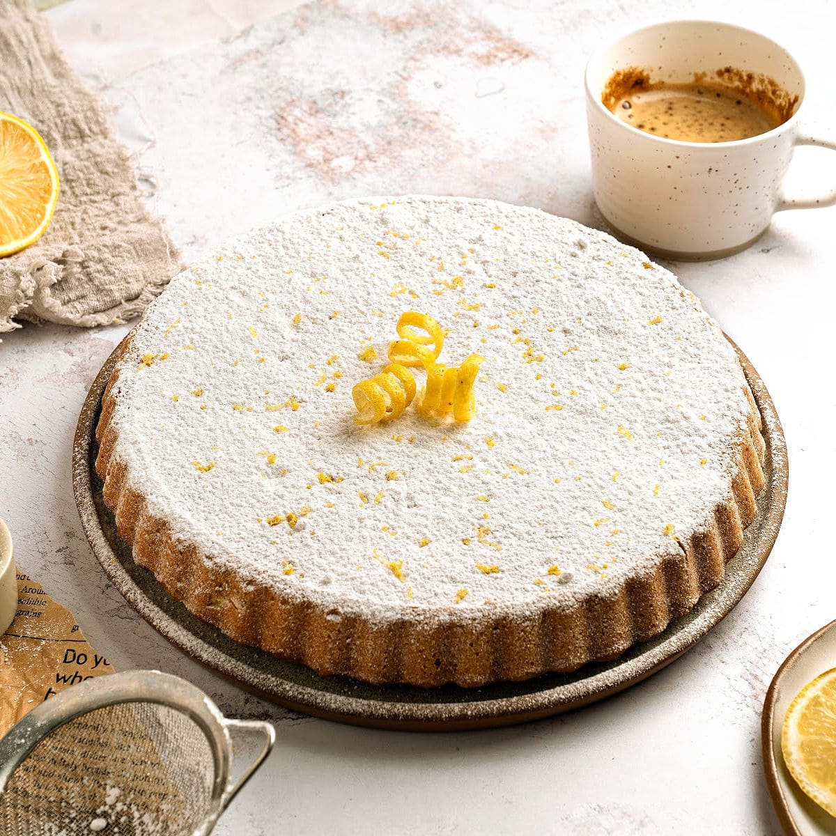 Whole double crust lemon ricotta pie with powdered sugar on a plate. White and beige background, coffee cup.