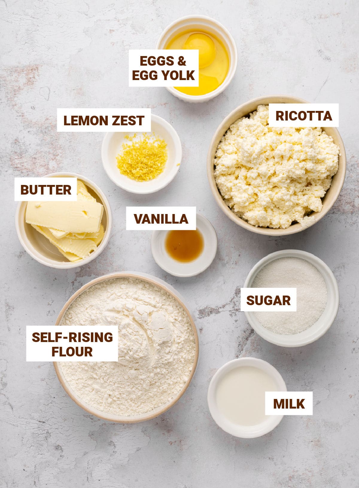 Light gray background with white bowls containing ingredients for lemon ricotta pie.