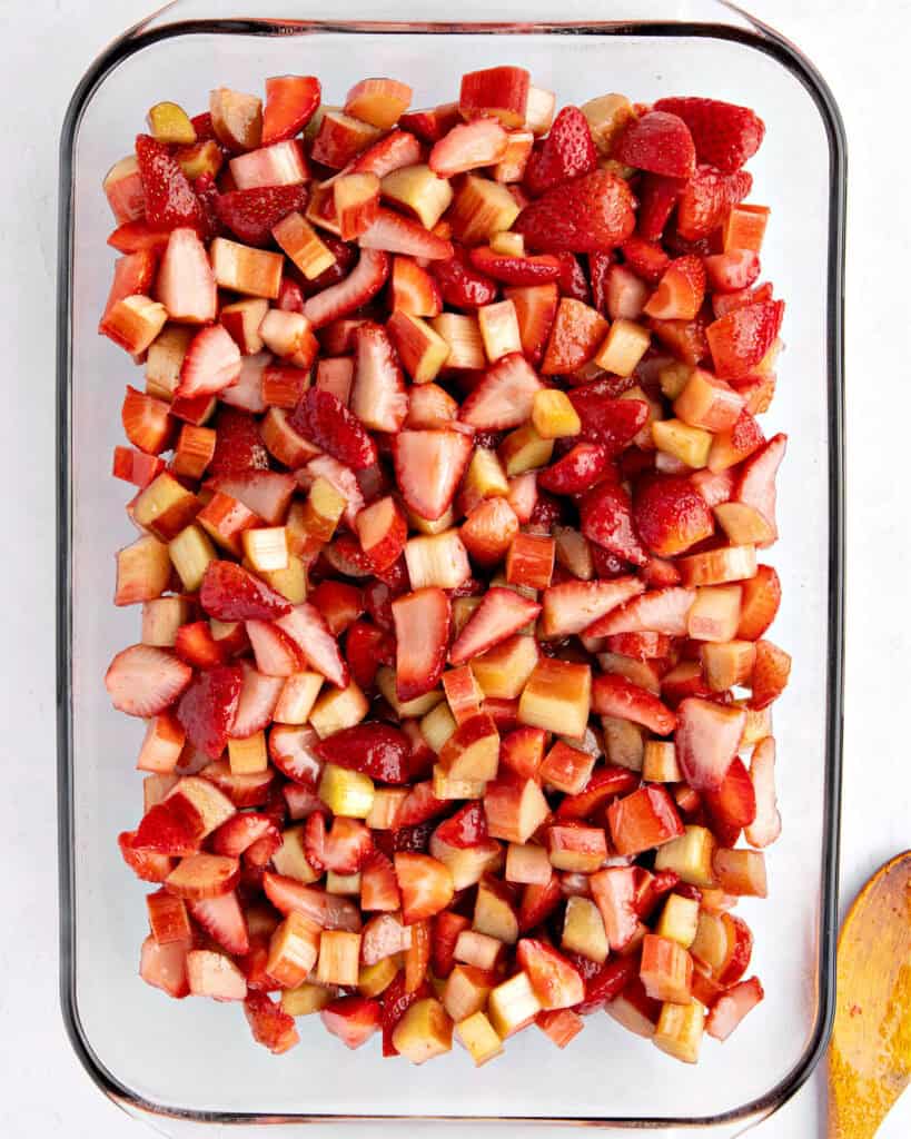 Glass baking dish with pieces of strawberry and rhubarb. White background. Top view.