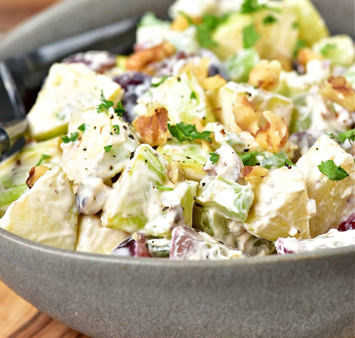Gray bowl with classic Waldorf salad with chopped walnuts.