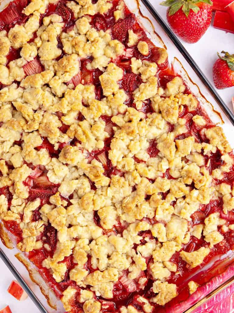 Baked strawberry rhubarb crisp in a glass baking dish. Fresh strawberries.