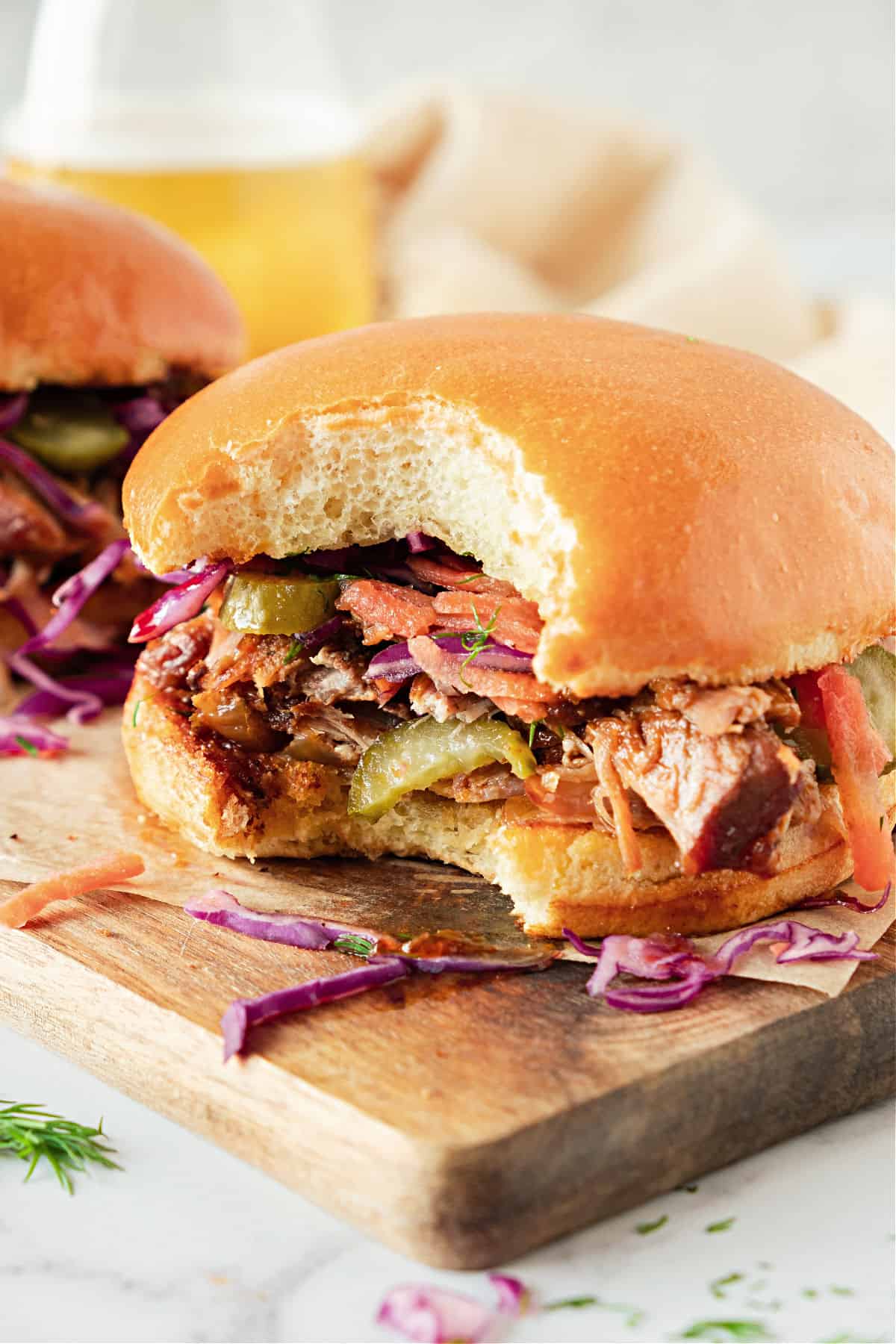 Bitten pulled pork burger with pickles and coleslaw. Wooden board.