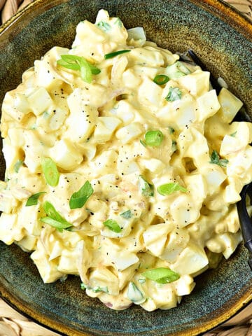 Old fashioned egg salad with mayo in a brownish green bowl.