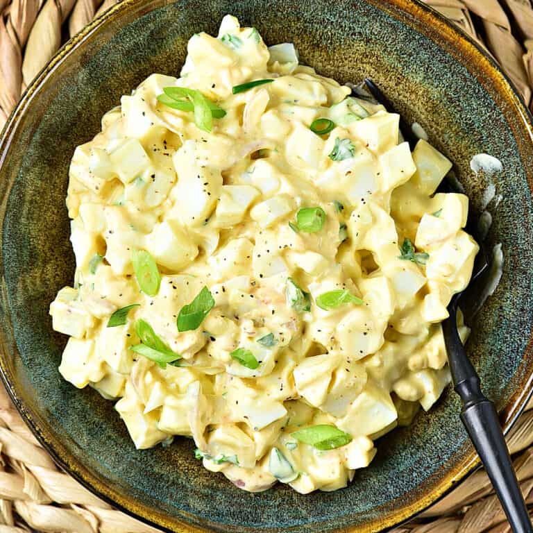 Old fashioned egg salad with mayo in a brownish green bowl.