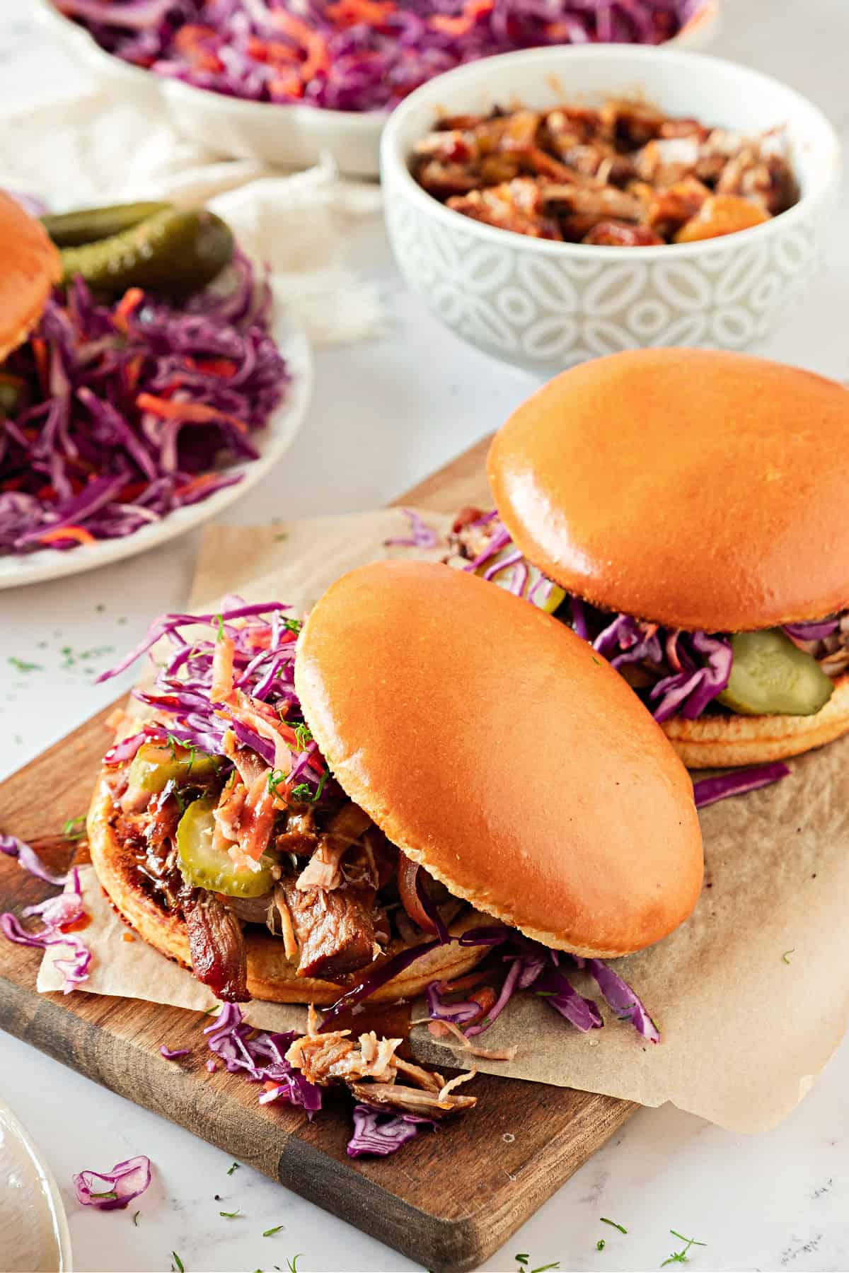 Pork burgers with coleslaw on a wooden board.