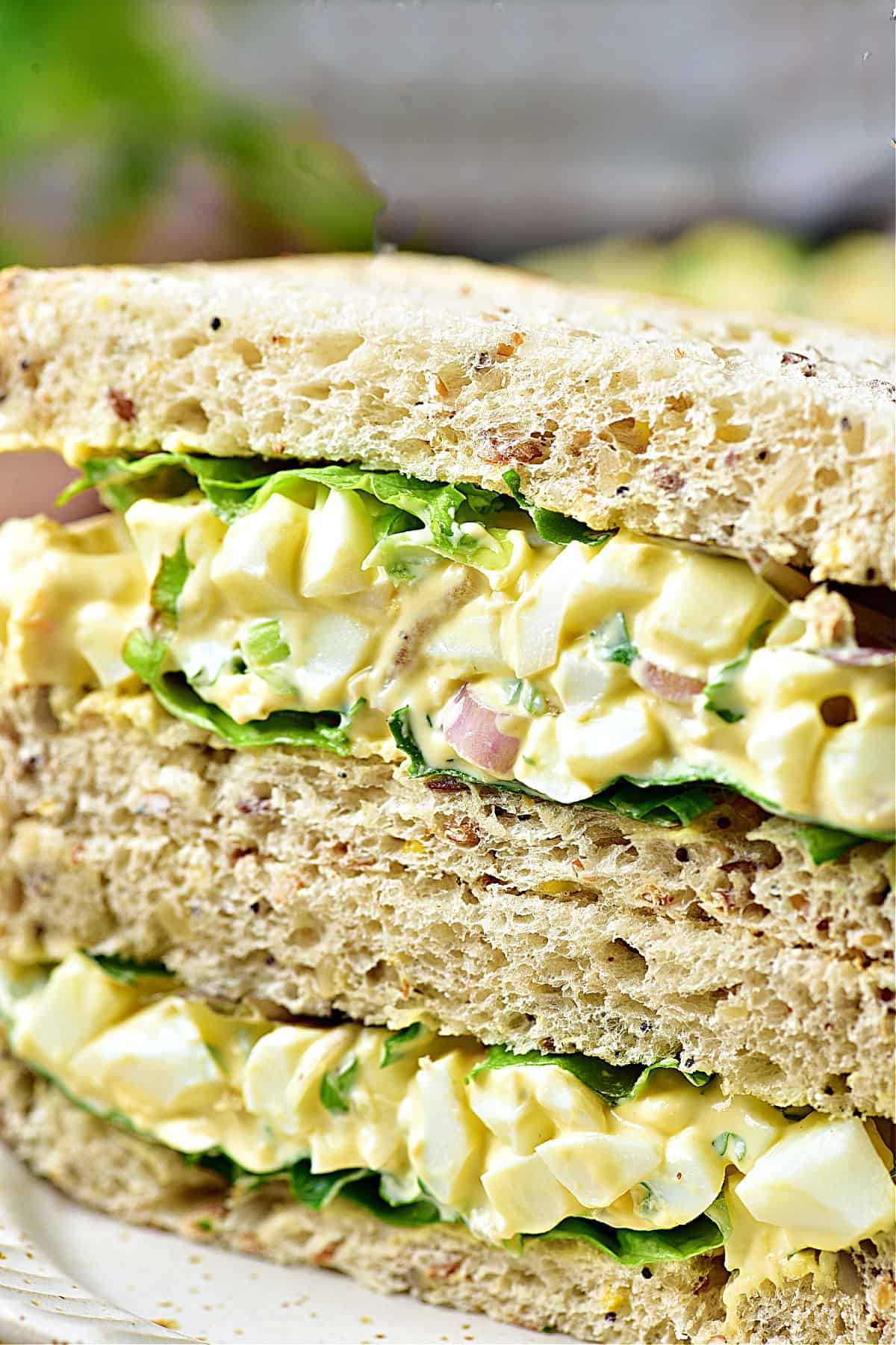 Close up egg salad on whole wheat sandwich halves.