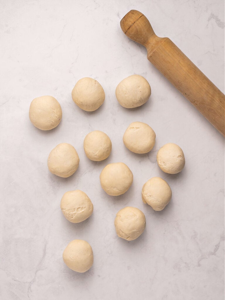 Small dough balls on a light gray background. A rolling pin.