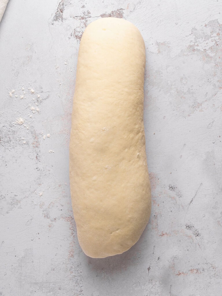Formed loaf of white bread on a light gray background.
