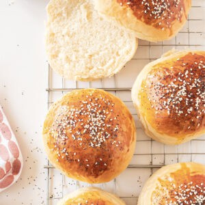 Wire rack with seeded burger buns. White background.