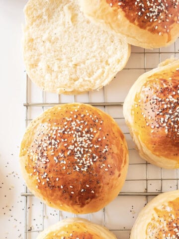 Wire rack with seeded burger buns. White background.