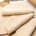 Brown and white text overlay on empanada dough discs and rolling pin.