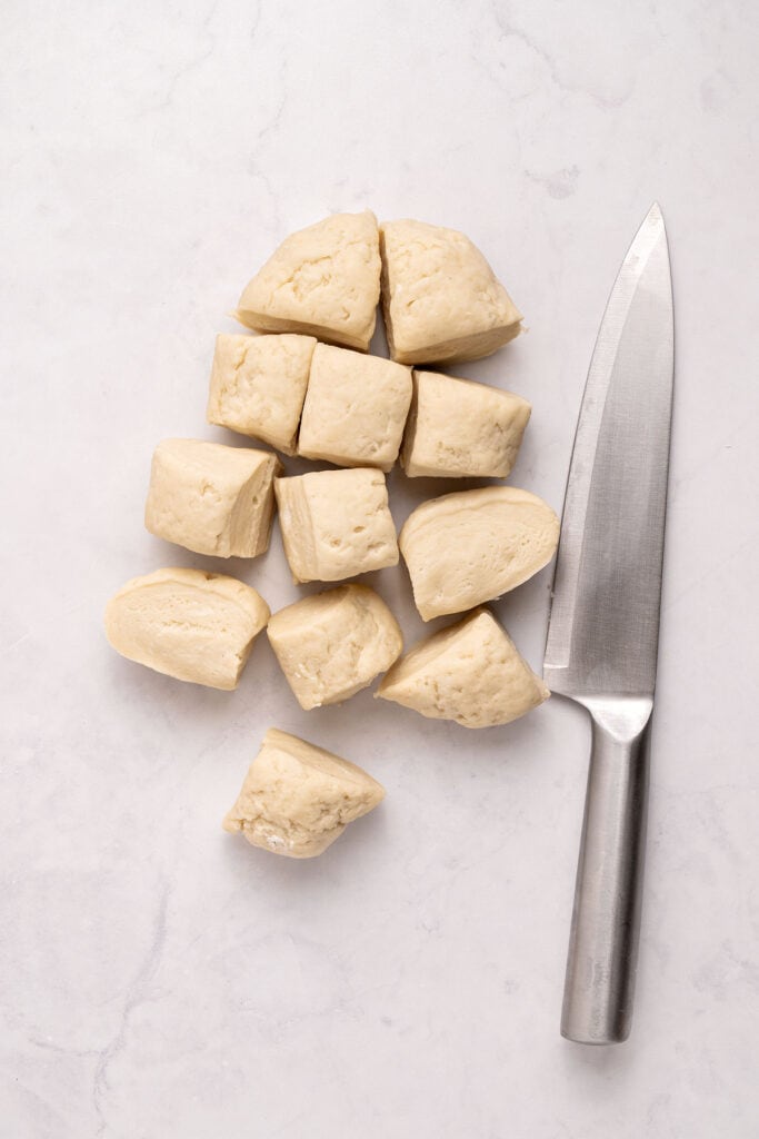 Light gray surface with a kitchen knife and small portions of dough.