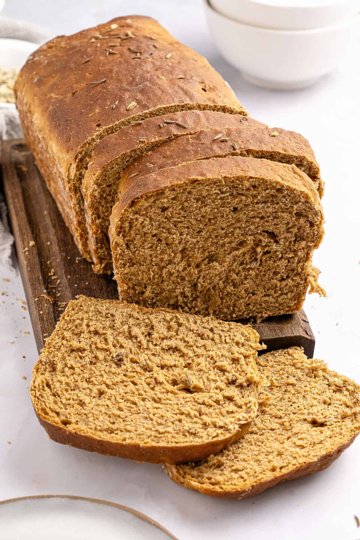 Finnish Pulla (Cardamom-scented sweet bread) Sliced loaf of rye sandwich bread on a wooden board. White background.